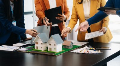balancing the property sector The real estate agent is explaining the house style to see the house design and the purchase agreement. model house at modern office